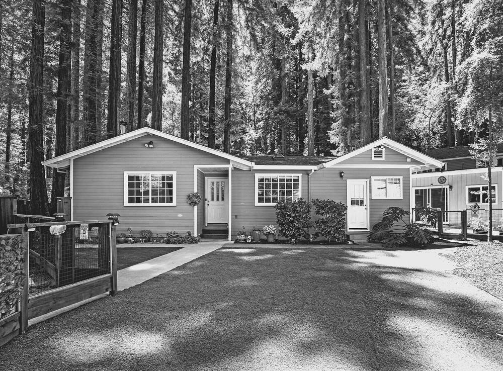 Single-story home at 17515 Comanche Trail with a fenced front yard, set among tall redwoods
